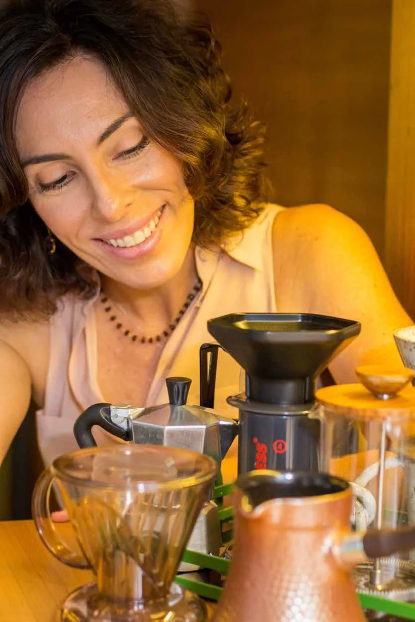 Letícia Paiva sorrindo enquanto prepara café com diferentes métodos